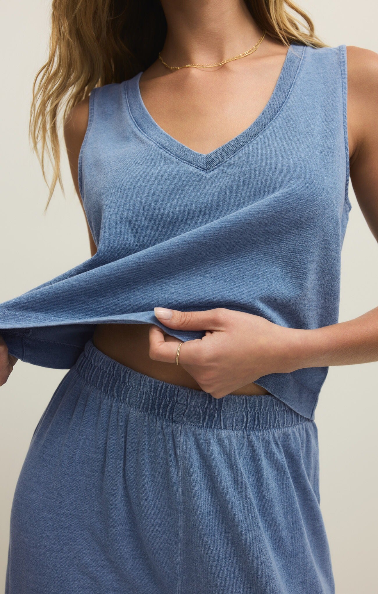 Person wearing a blue sleeveless top and shorts against a neutral background