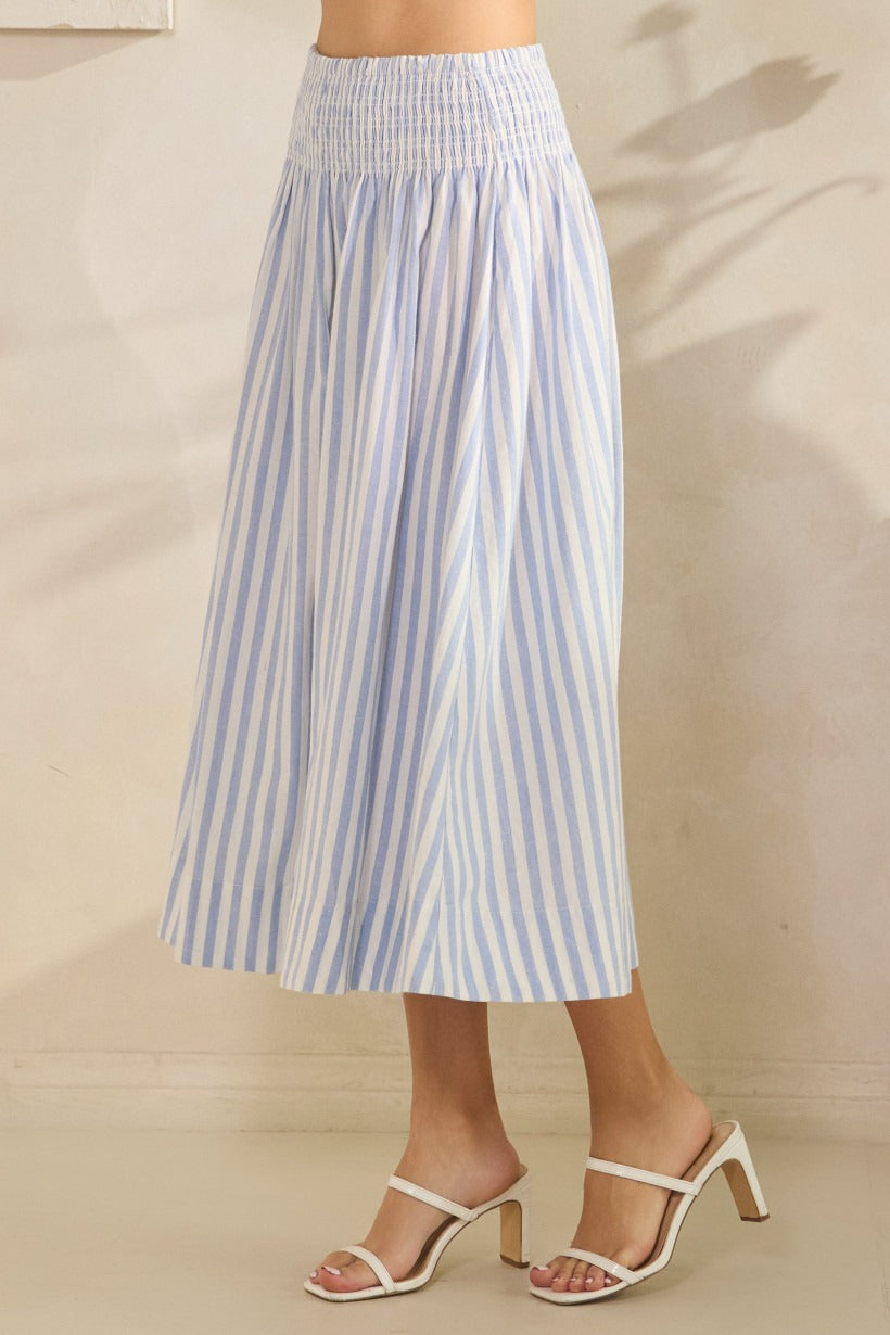 Person wearing a blue and white striped skirt on a beige background