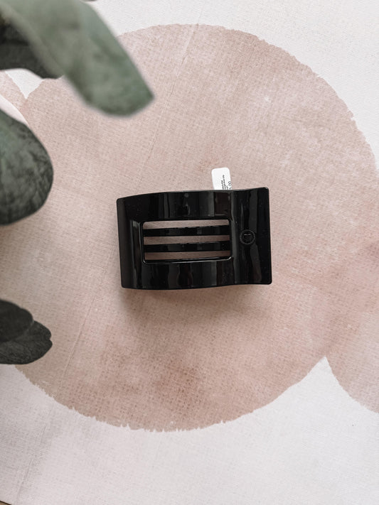 Black hair clip on a beige circular background