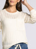Woman wearing a cream-colored knit sweater against a plain background