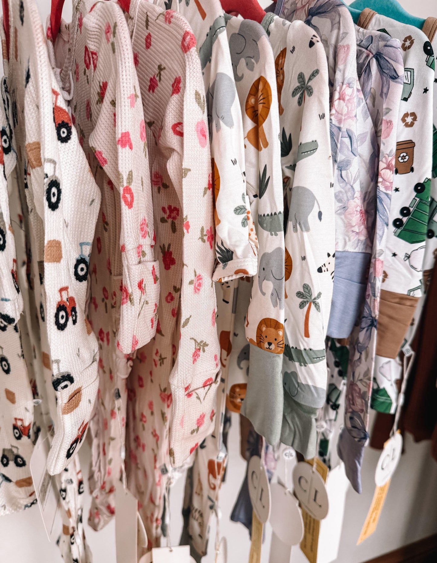 Collection of baby rompers with various patterns on a rack.