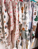 Collection of baby rompers with various patterns on a rack.