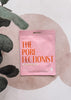 Pink 'The Pore-Fectionist' mask packaging on a textured surface with leaves.