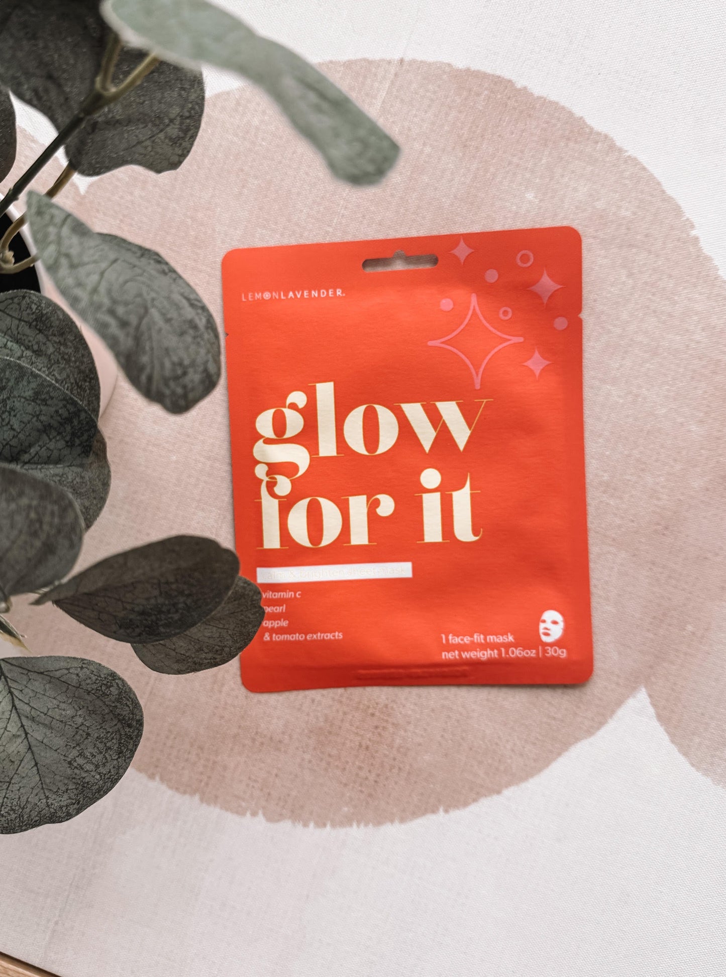 Red package with 'glow for it' text on a light background with leaves.