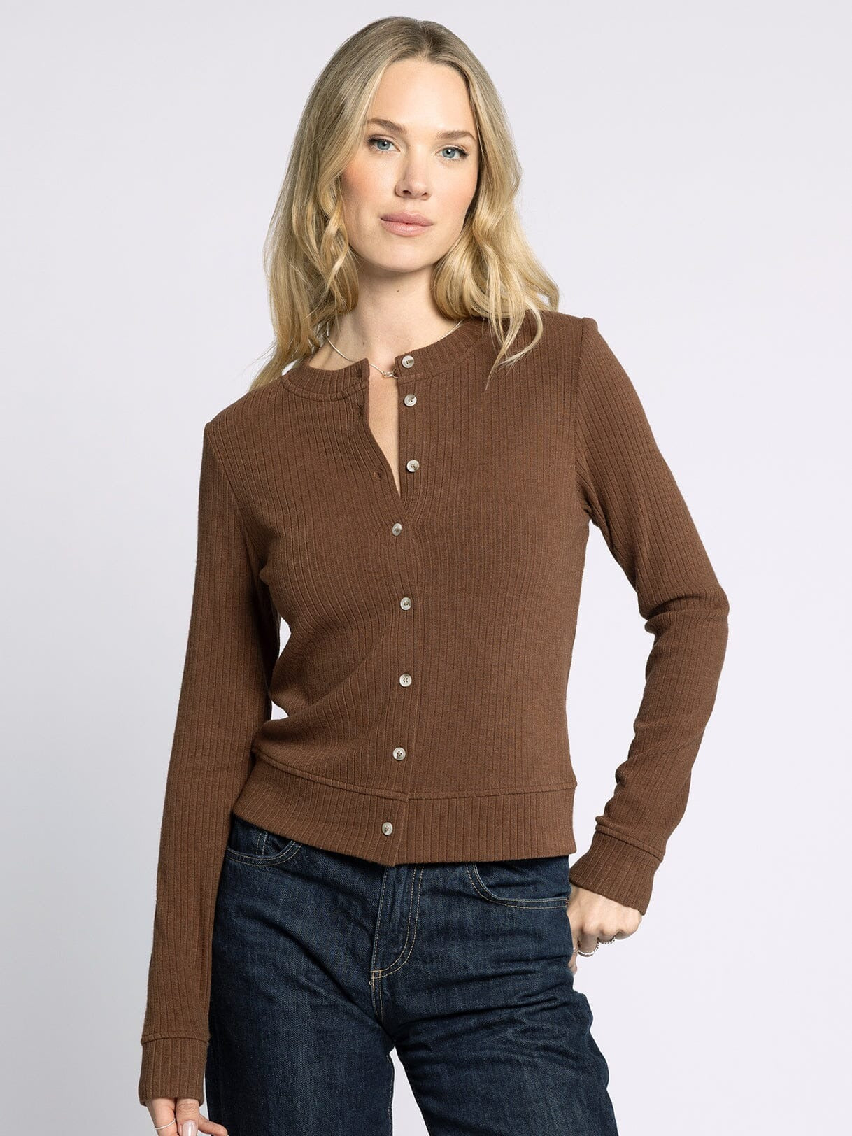Woman wearing a brown cardigan with a plain background