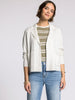Woman wearing a white blazer, striped shirt, and blue jeans on a plain background