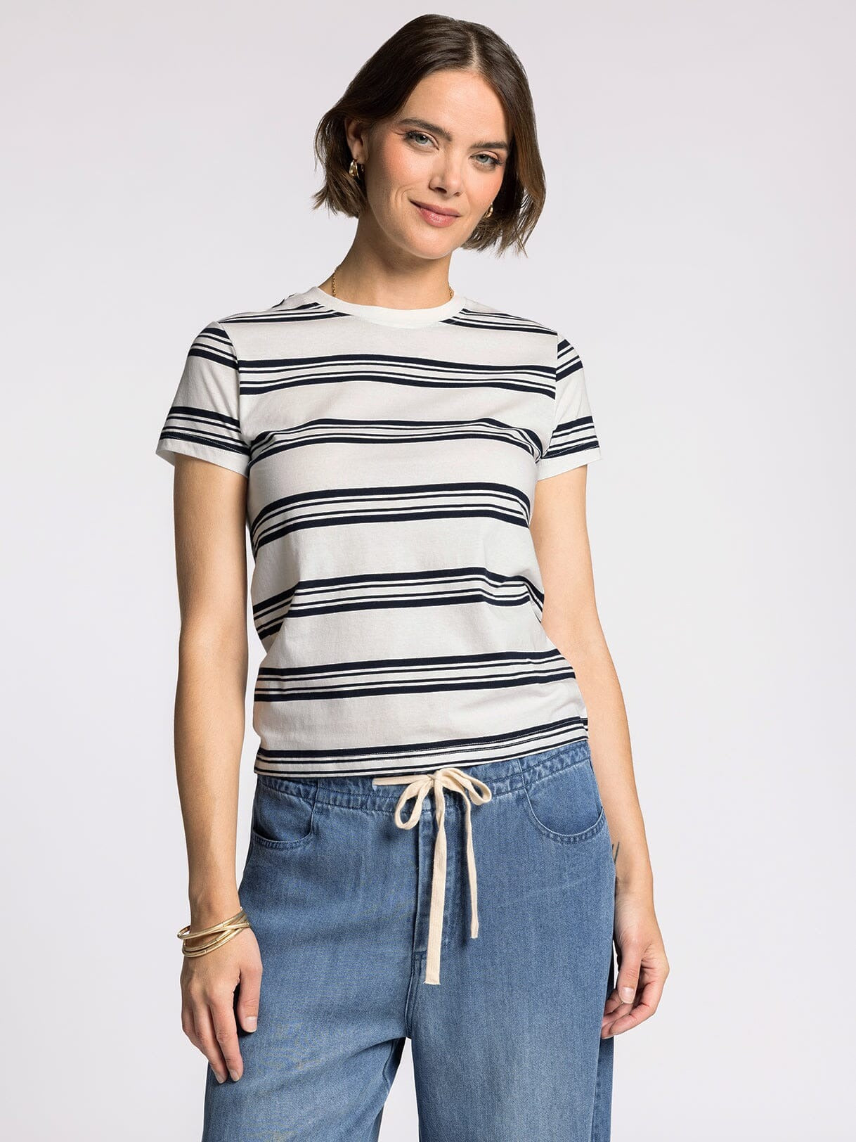 Woman wearing a striped shirt and jeans on a plain background