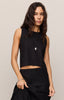 Woman wearing a black sleeveless top and black pants against a plain background