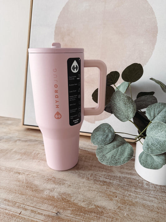 Pink Hydroflask mug on a wooden surface with a plant in the background