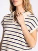 Woman wearing a beige and navy striped shirt against a white background