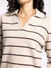 Close-up of a person wearing a cream sweater with burgundy stripes.