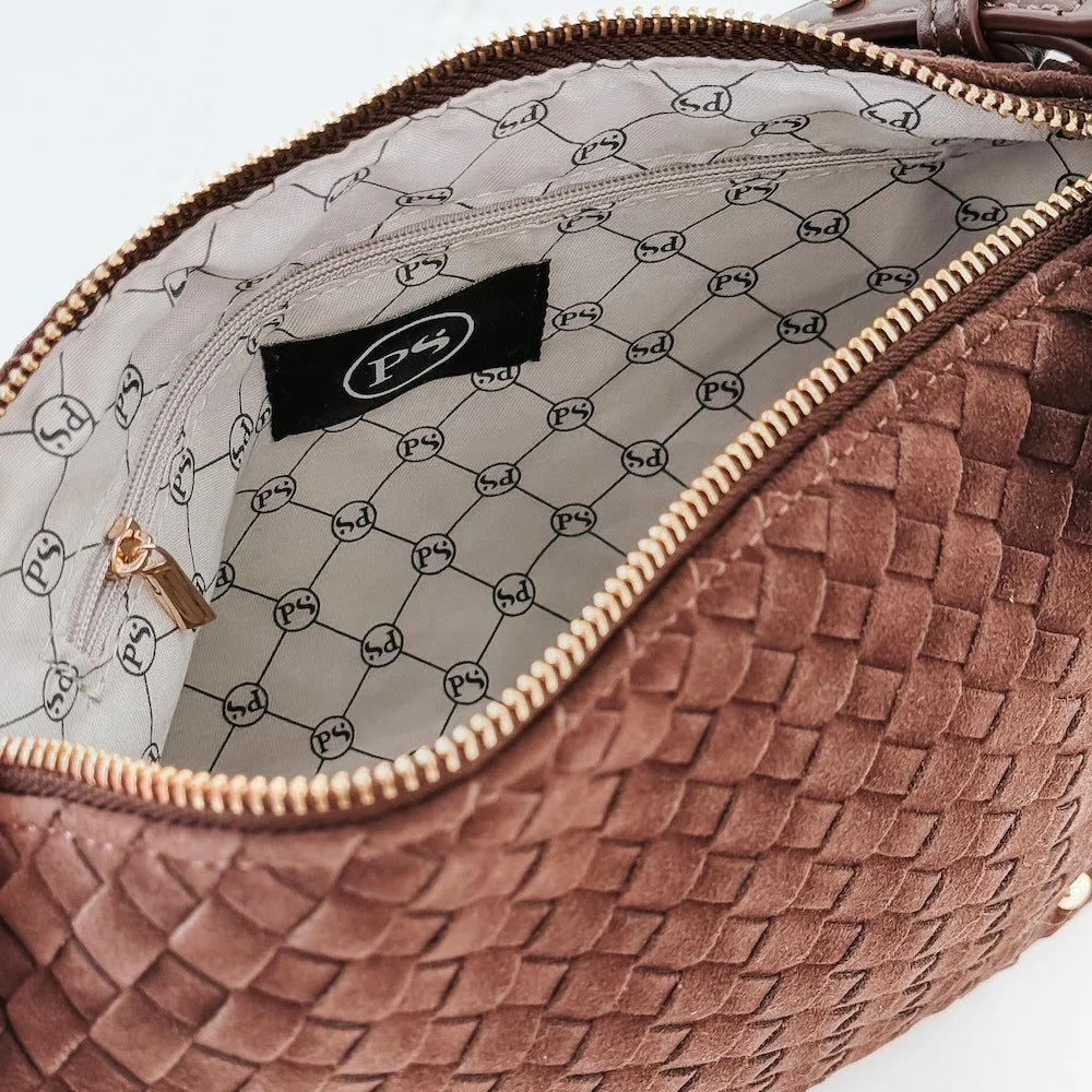 Close-up of a brown textured handbag with a brand label on a light gray background