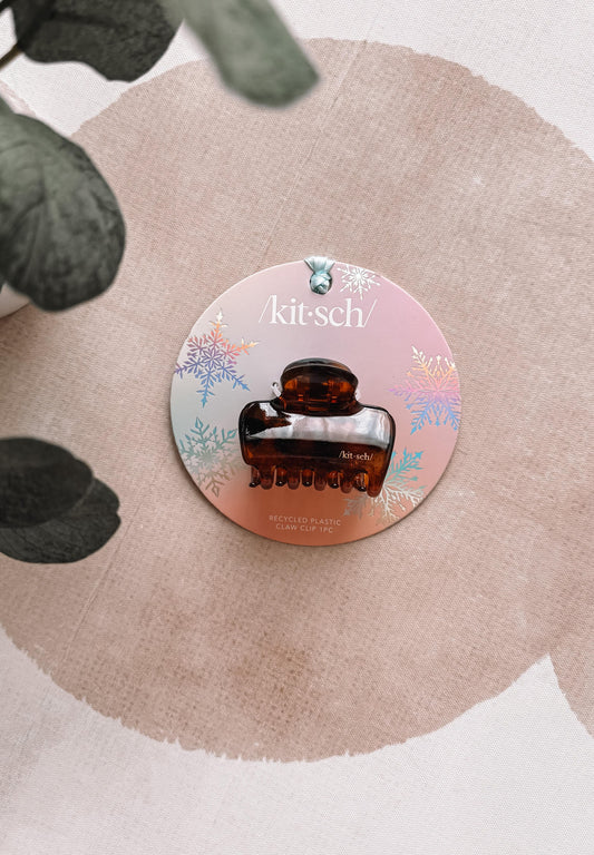 Round hair clip packaging with 'kitsch!' branding on a beige background
