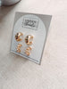 Gold earrings on a card with 'Urban Threads' branding on a light surface