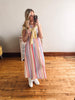 Woman taking a mirror selfie wearing a colorful striped dress and yellow scarf in a room with wooden flooring.