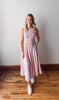 Woman wearing a striped dress standing on a wooden floor with a white wall background