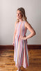 Woman wearing a colorful striped dress standing on a wooden floor.
