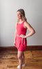 Woman wearing a red dress with white trim standing on a wooden floor.