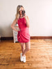 Woman taking a mirror selfie wearing a red dress and white sneakers on a wooden floor.