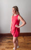 Woman wearing a red dress standing on a wooden floor with a plain wall background