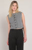 A woman modeling a sleeveless gray cable-knit cropped vest with dark buttons, paired with black trousers, against a plain light gray studio background.