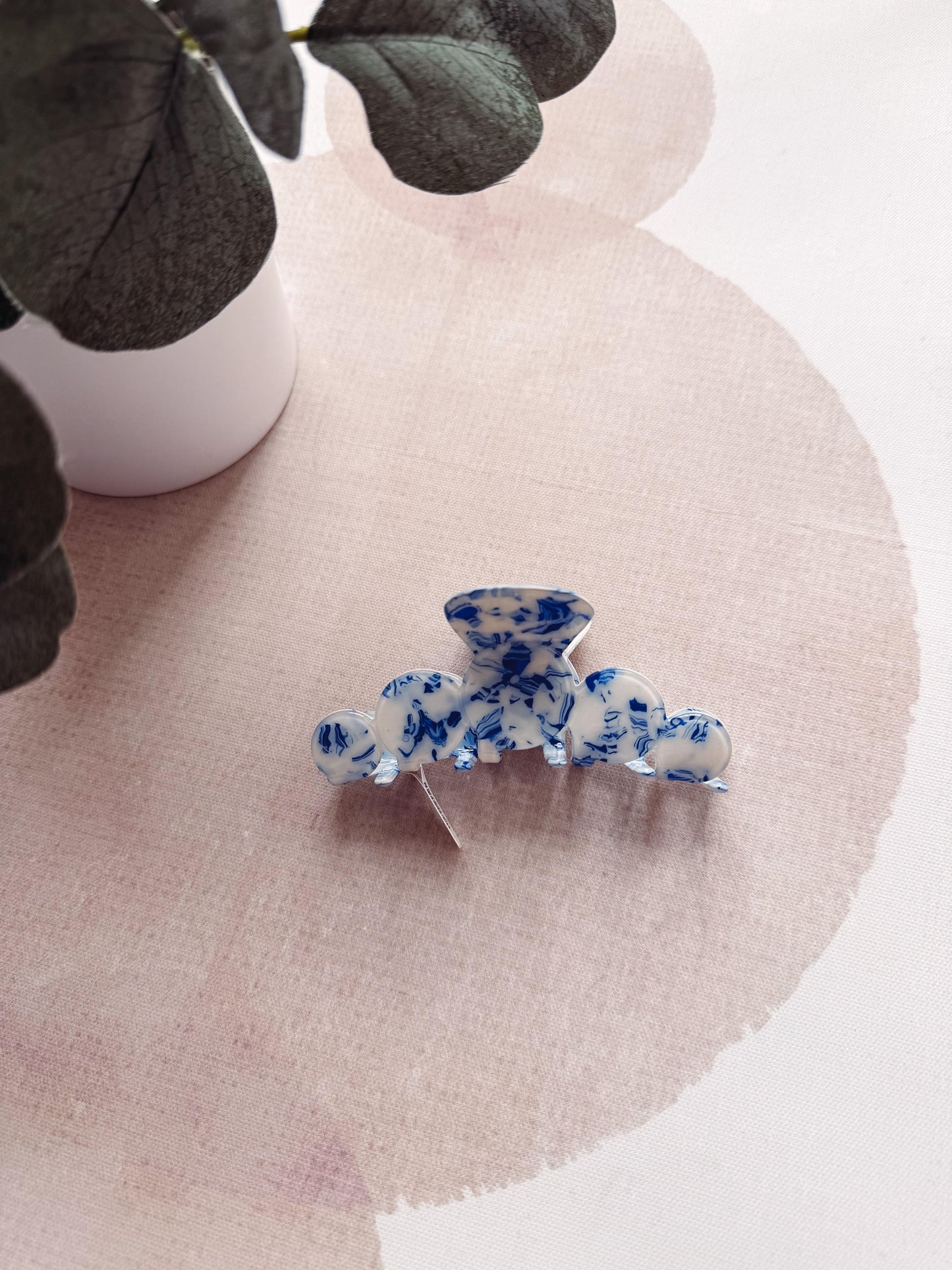 Blue and white floral hair clip on a pink fabric background