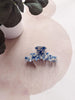 Blue and white floral hair clip on a pink fabric background