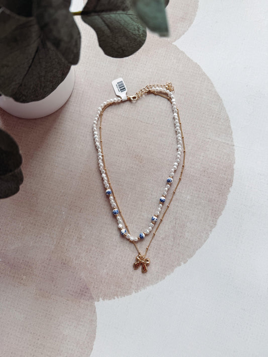 Necklace with a star-shaped pendant on a beige surface with a plant in the background
