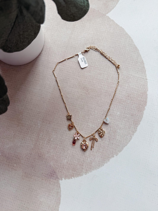 Necklace with charms on a pink fabric background