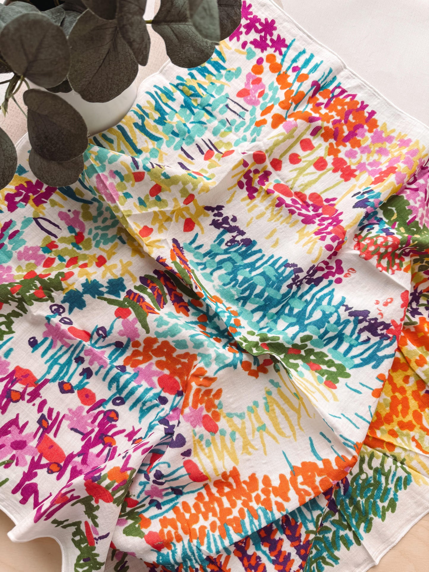 Colorful floral-patterned fabric with a plant in the background