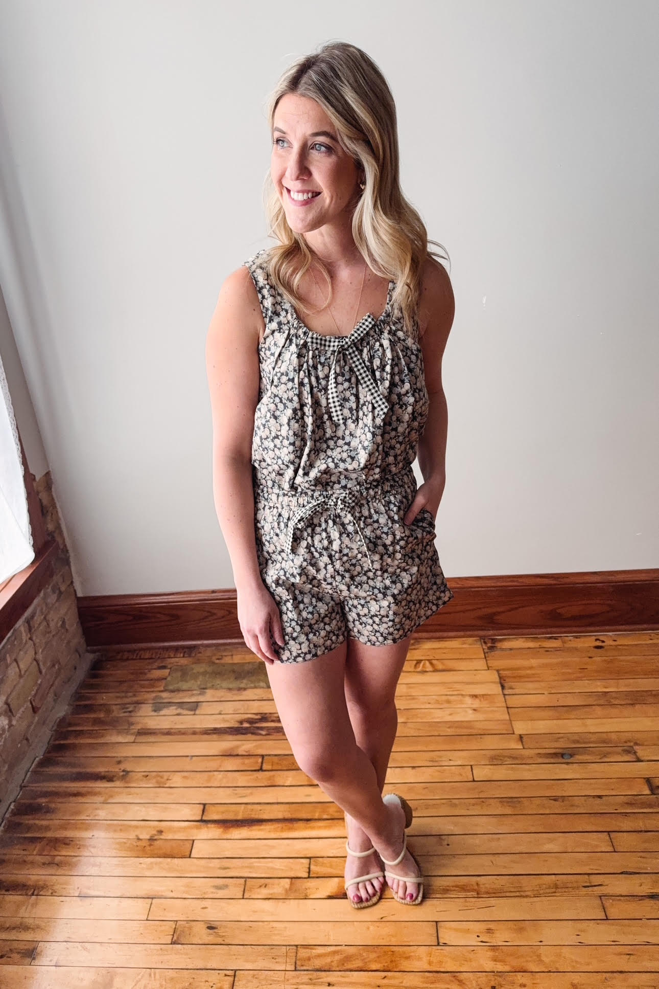 Woman wearing a patterned romper standing on a wooden floor.