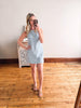 Woman taking a mirror selfie wearing a blue and white striped dress in a room with wooden flooring.