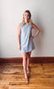 Woman wearing a striped dress standing on a wooden floor against a white wall