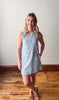 Woman wearing a blue and white striped dress standing on a wooden floor.