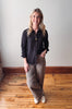 Woman wearing a black shirt and leopard print pants standing on a wooden floor.