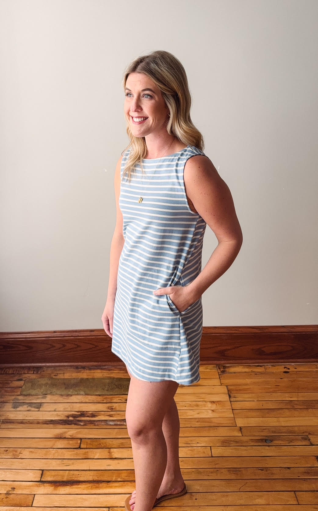 Woman wearing a blue and white striped dress standing on a wooden floor.