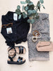 Black shirt, leopard print pants, sandals, beige handbag, sunglasses, and a plant on a light surface.