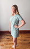 Woman wearing a green and white striped dress standing on a wooden floor.