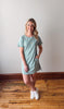 Woman wearing a striped dress standing on a wooden floor with a white wall background