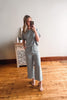 Woman taking a mirror selfie wearing a light blue outfit in a room with wooden flooring and a decorative cabinet.