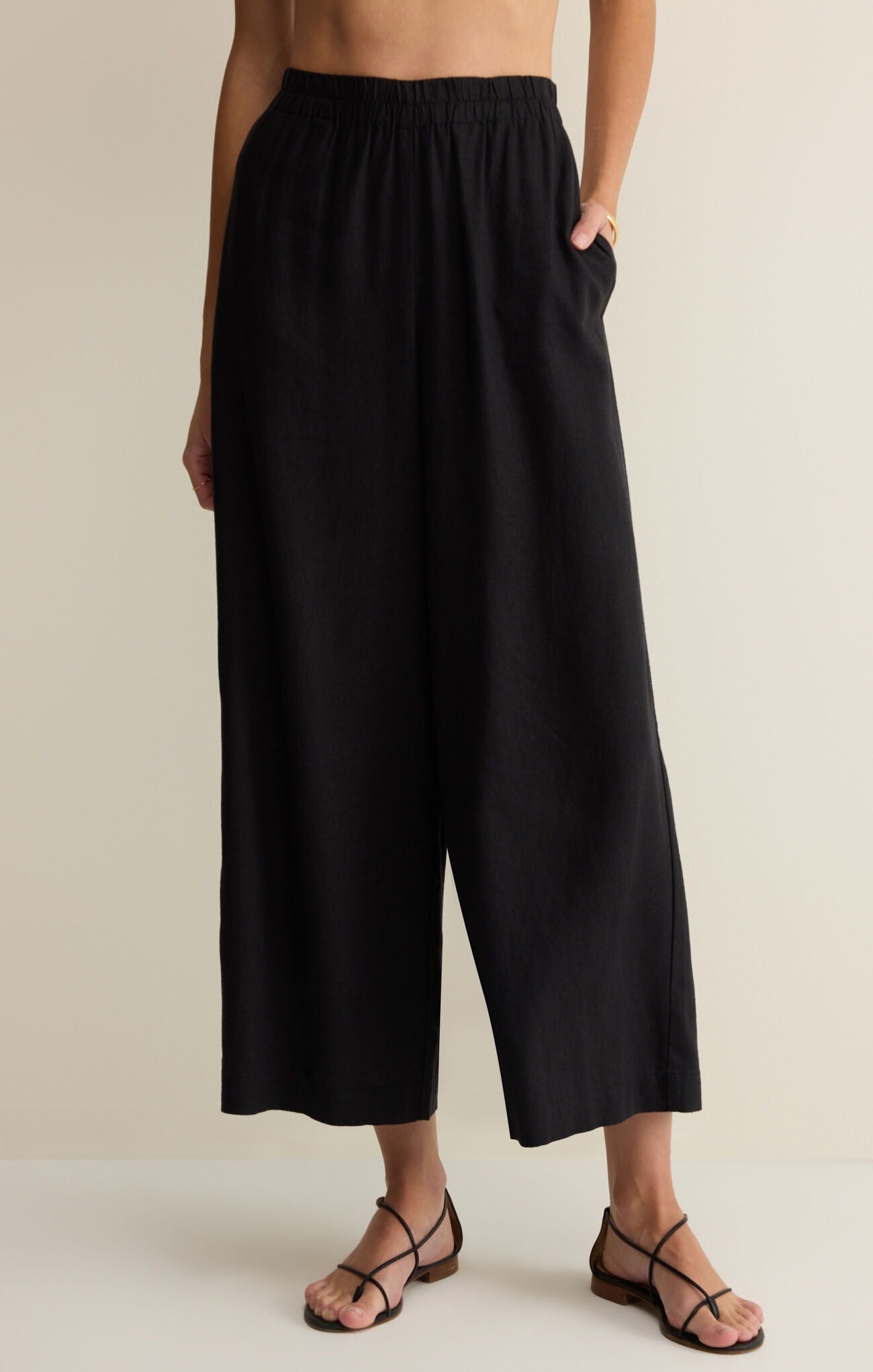 Person wearing black wide-leg pants on a beige background