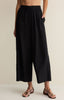 Person wearing black wide-leg pants on a beige background