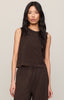 Woman wearing a brown sleeveless top and pants against a neutral background